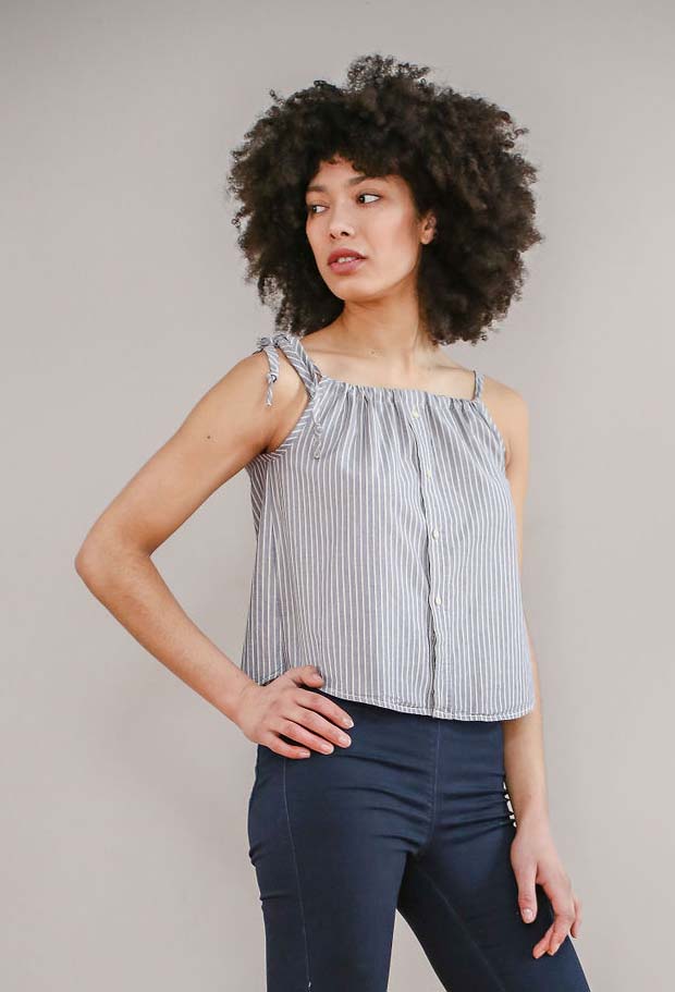 Woman wearing the Tweedsmuir Top sewing pattern from Greyfriars and Grace on The Fold Line. A sleeveless sun top pattern made in lightweight woven fabrics, featuring an up-cycled shirt with front button closure, adjustable drawstring shoulder straps and b