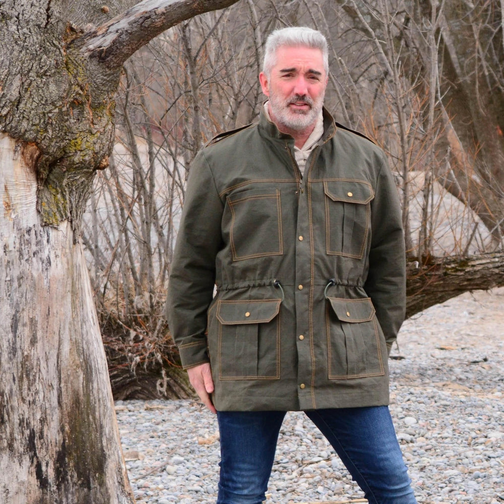Man wearing the Men's Utility Jacket sewing pattern from Wardrobe by Me on The Fold Line. A jacket pattern made in coated twill or canvas fabrics, featuring a zipper with a buttoned wind guard, several pockets, two-piece sleeves, epaulettes and adjustable