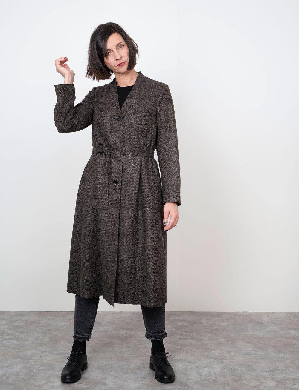 Woman wearing the V-Neck Coat sewing pattern from The Assembly Line on The Fold Line. A coat pattern made in cotton twill, lightweight canvas or wool fabrics, featuring a stand-up collar, V-neck opening, three buttons mid-front, side seam pockets and self