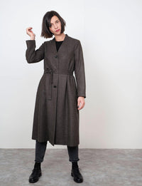 Woman wearing the V-Neck Coat sewing pattern from The Assembly Line on The Fold Line. A coat pattern made in cotton twill, lightweight canvas or wool fabrics, featuring a stand-up collar, V-neck opening, three buttons mid-front, side seam pockets and self