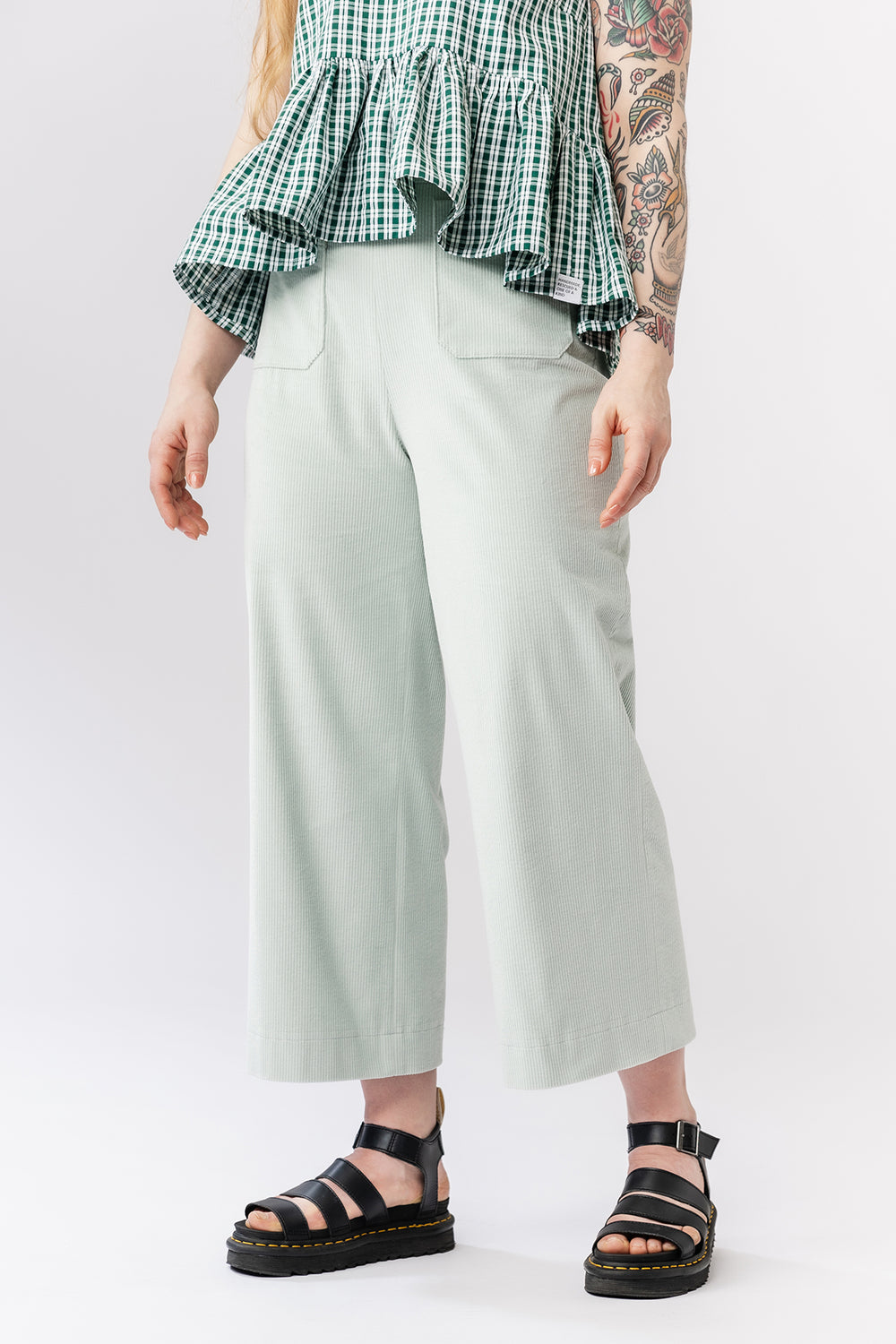 Woman wearing the Verso Trousers sewing pattern from Named on The Fold Line. A trousers pattern made in cotton or linen fabric, featuring a high waist, straight leg, invisible zipper, patch pockets, and cropped length.