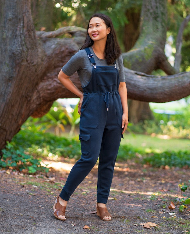 Woman wearing the Varzim Overalls sewing pattern from Itch to Stitch on The Fold Line. A dungarees pattern made in sweatshirt fleece with elastane or ponte fabrics, featuring a drawstring waist, adjustable shoulder straps, chest, back and side leg pockets