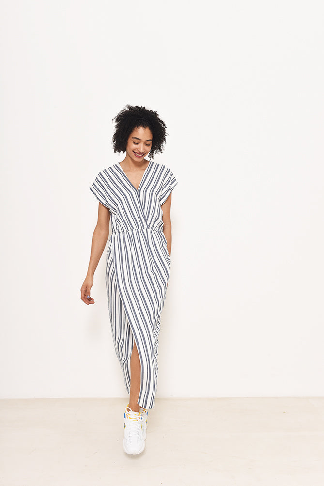 Woman wearing the Vienna Dress sewing pattern from Fibre Mood on The Fold Line. A faux wrap dress pattern made in fluid drape fabrics and avoid stiff fabrics, featuring a wrap top stitched in place at the waist, V-neck, short grown on sleeves, elasticated