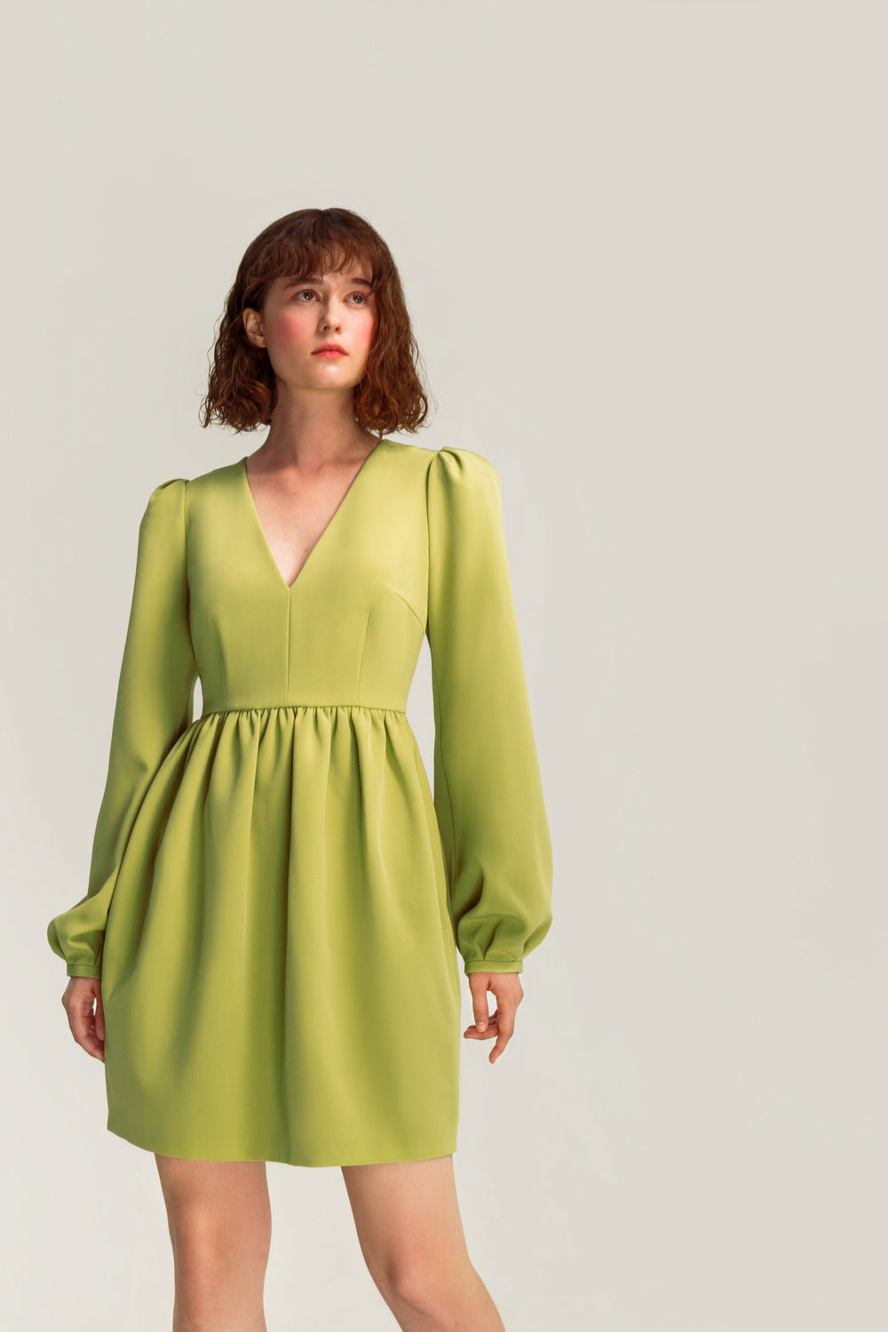 Woman wearing the Violet Dress sewing pattern from Vikisews on The Fold Line. An dress pattern made in gabardine, suiting, velvet, dress-weight fine wale corduroy, or modal fabrics, featuring a close-fitting bodice, gathered skirt, waist seam, bust and wa