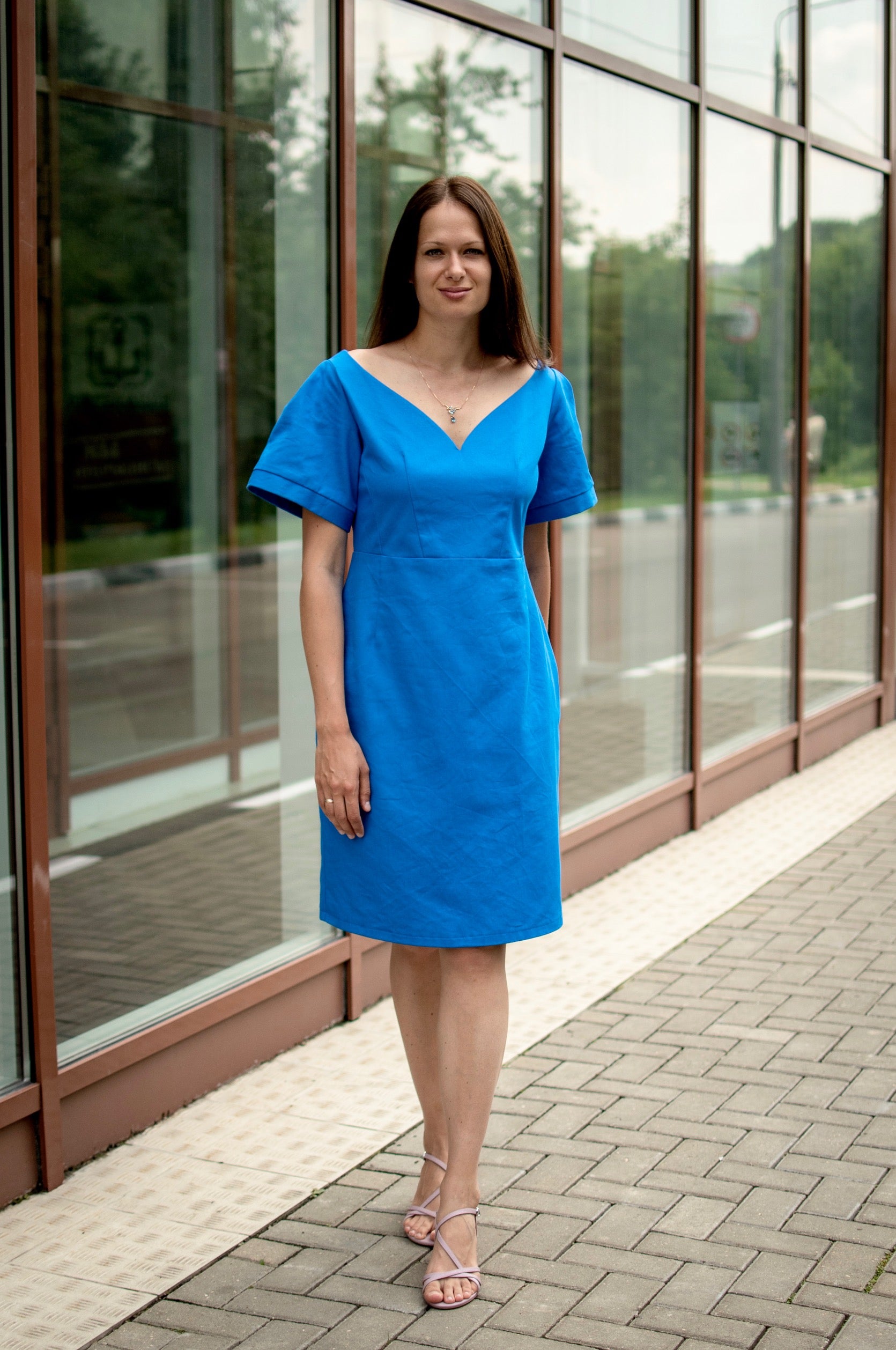 Woman wearing the Vivian Dress sewing pattern from Kates Sewing Patterns on The Fold Line. A panelled dress pattern made in dense cotton or denim fabrics, featuring a low curved neckline, slightly raised waistline, waist, bodice and shoulder darts, knee l