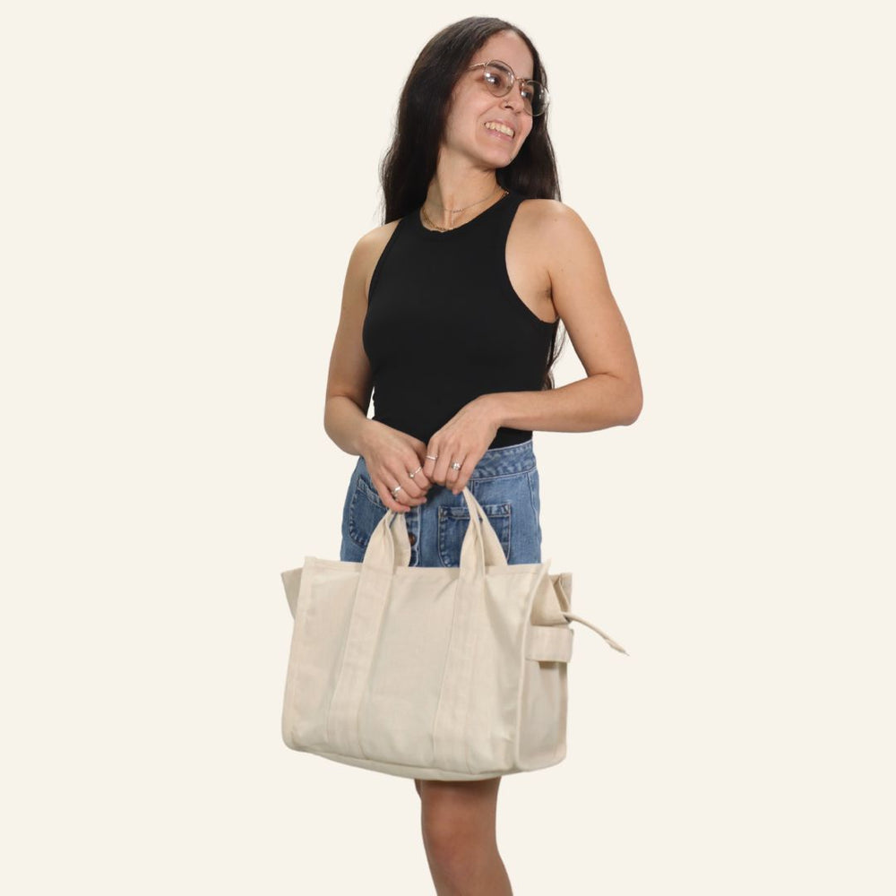 Woman holding the Viviana Tote Bag sewing pattern from Sirena Patterns on The Fold Line. A bag pattern made in canvas, duck cloth, sail cloth, heavyweight denim, or upholstery fabric, featuring side panels, a top zippered closure with an end tab, top and 