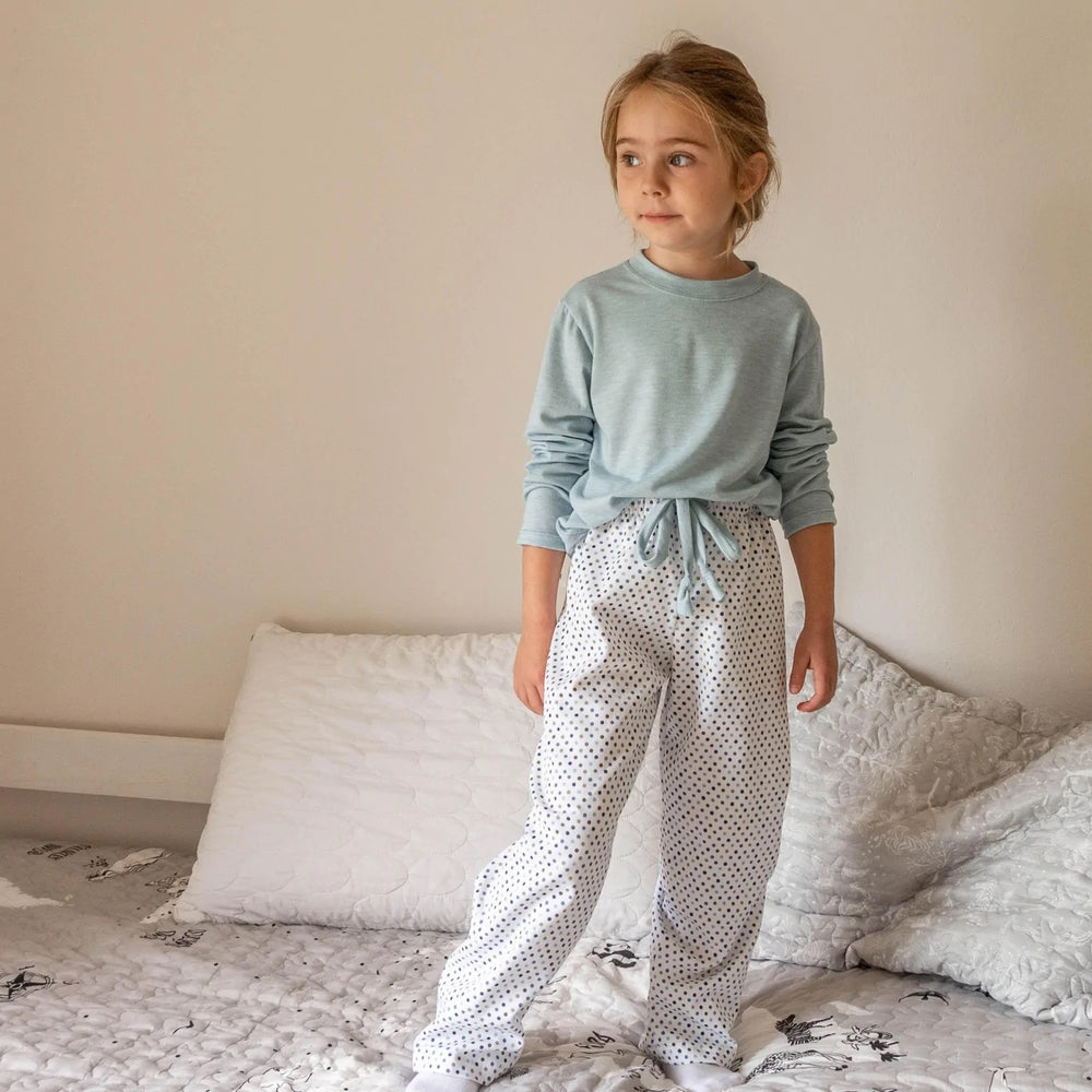 Child wearing the Children's PJ Pants sewing pattern from Wardrobe by Me on The Fold Line. A pyjama trouser pattern made in cotton, silk or viscose fabrics, featuring an elastic and drawstring waist, no side seams, back patch pocket and relaxed fit.
