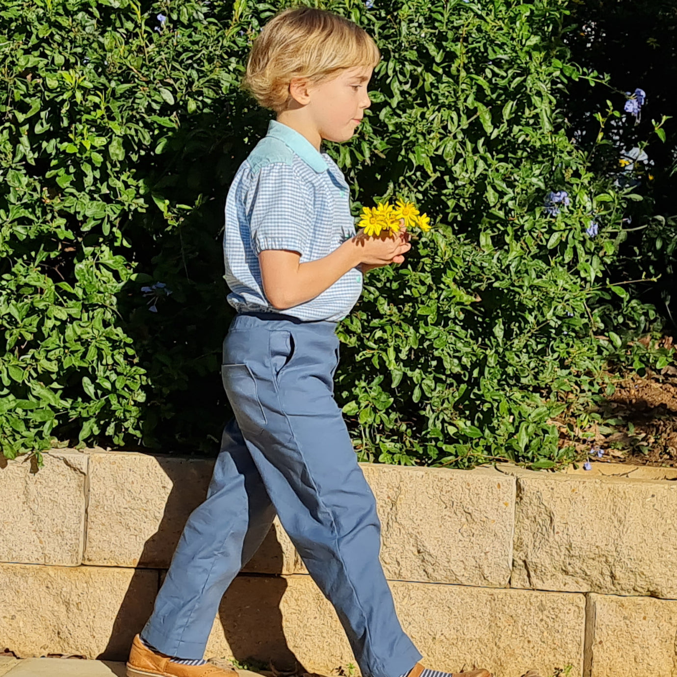 Child wearing the Children's Woven Pants sewing pattern from Wardrobe by Me on The Fold Line. A pull-on trouser pattern made in cotton, light canvas, denim or linen fabrics, featuring an elastic waist, straight leg, side and back pockets and decorative fr