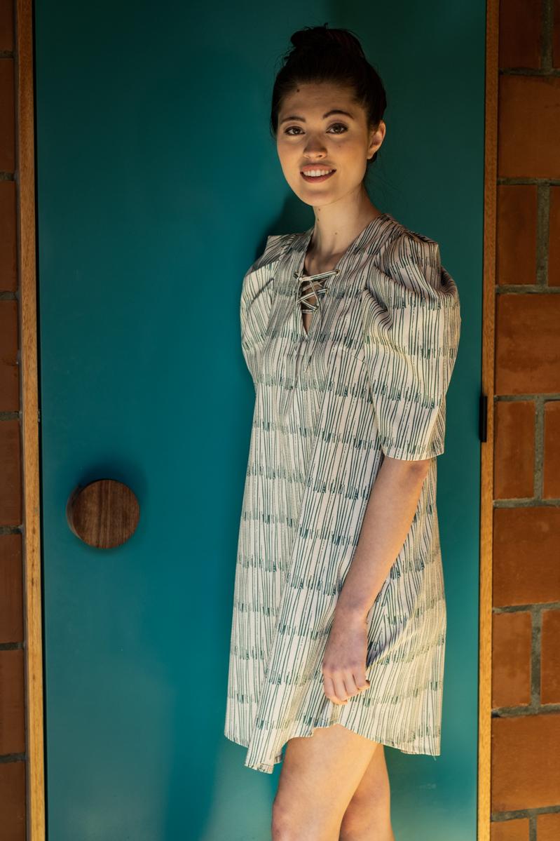 Woman wearing the Wanda Dress sewing pattern from Fibre Mood on The Fold Line. A dress pattern made in corduroy, denim, poplin, viscose (crepe) or lyocell fabrics, featuring elbow length gathered sleeves, side seam pockets, lace-up décolleté with metal ey