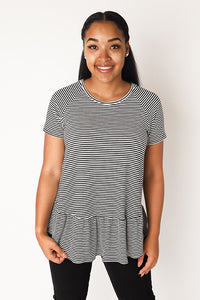 Woman wearing the Waterfall Raglan Top sewing pattern by Chalk and Notch. A dress pattern made in light to medium weight 75% – 100% stretch knit fabrics, featuring short sleeves, jewel neckline and ruffle.