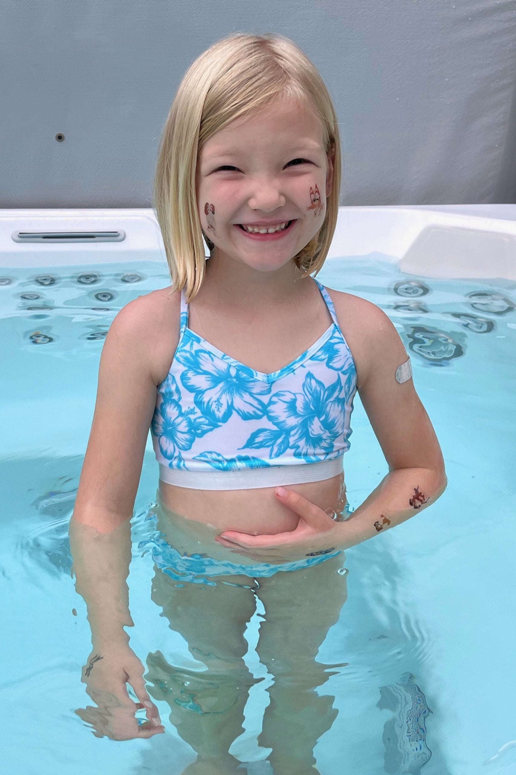 Child wearing the Children’s Olympia Sports Top sewing pattern from Waves & Wild on The Fold Line. A sports top pattern made in light to medium weight knit swim Lycra fabrics, featuring a close-fit, cropped length, V-neck, and straight back.