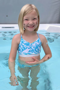 Child wearing the Children’s Olympia Sports Top sewing pattern from Waves & Wild on The Fold Line. A sports top pattern made in light to medium weight knit swim Lycra fabrics, featuring a close-fit, cropped length, V-neck, and straight back.