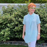 Woman wearing the Willow Blouse sewing pattern from The Sewing Workshop on The Fold Line. A blouse pattern made in wool challis, cotton, linen, silk or knit fabrics, featuring a semi-fit, front drape, two-button closure, collar, short set-in sleeves and a