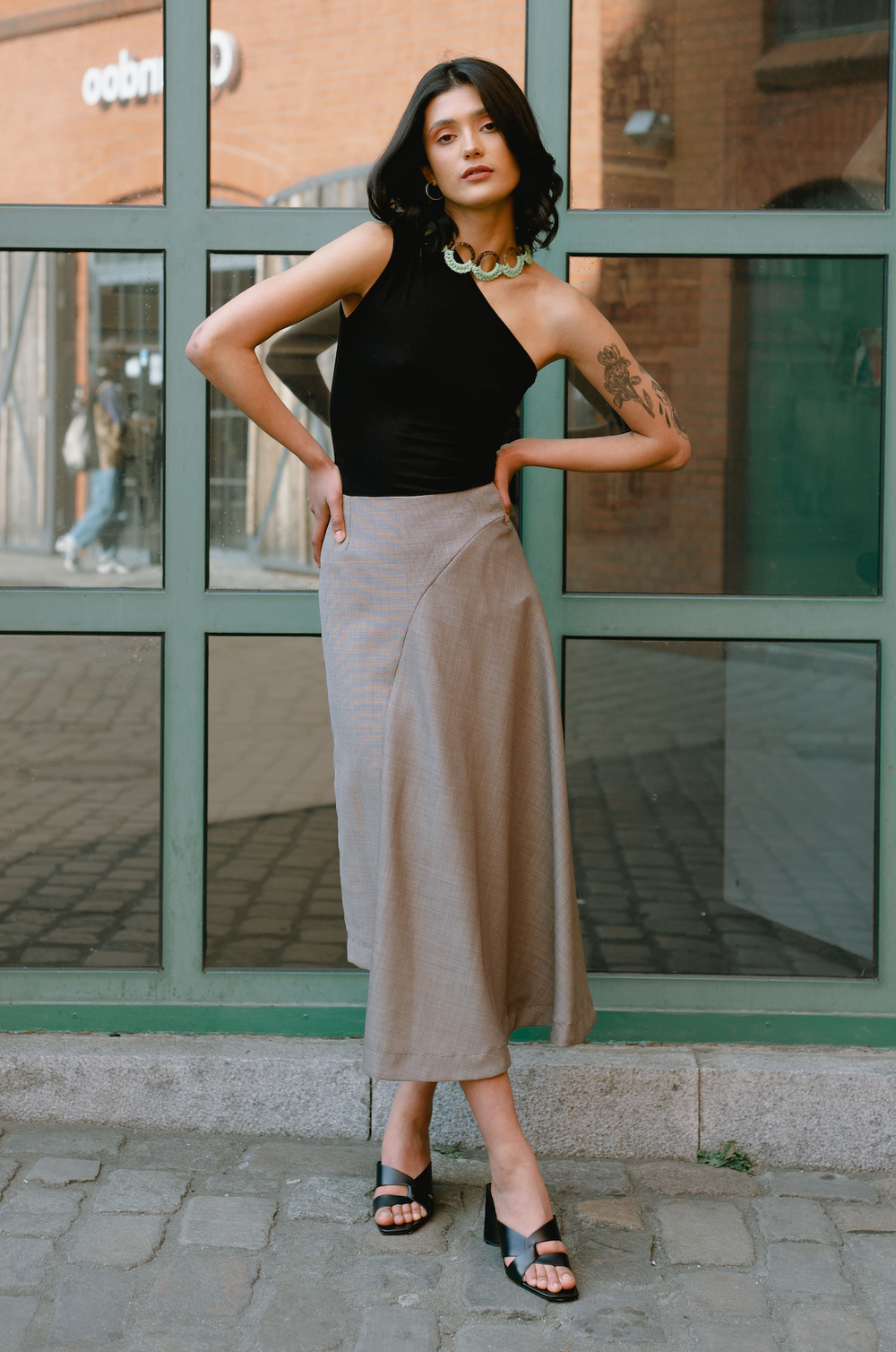 Woman wearing the Willow Skirt sewing pattern from JULIANA MARTEJEVS on The Fold Line. A skirt pattern made in wool or cotton fabrics, featuring an asymmetric silhouette, midi length, waist darts, and invisible zip closure.