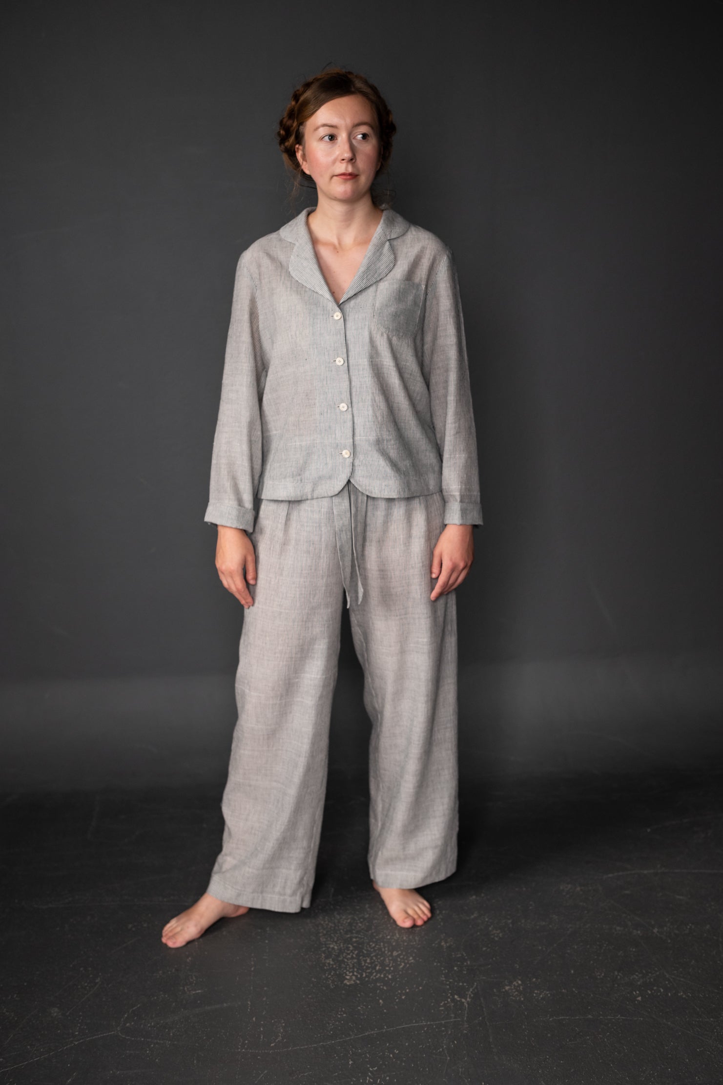Woman wearing the Winnie Pyjamas pattern from Merchant and Mills on The Fold Line. A pyjama pattern made in linen, brushed cotton, cotton lawn, cotton poplin, Tencel or cotton double gauze fabrics, featuring long sleeves, V-neck, button front closure, bre