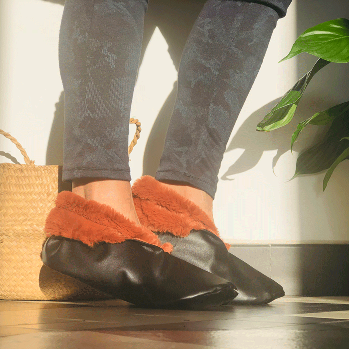 Woman wearing the YMMD Slippers sewing pattern from You Made My Day on The Fold Line. A slippers pattern made in fleece, faux fur, leather or cotton fabrics, featuring a leather sole, upper and sides with faux fur cuff and lining.