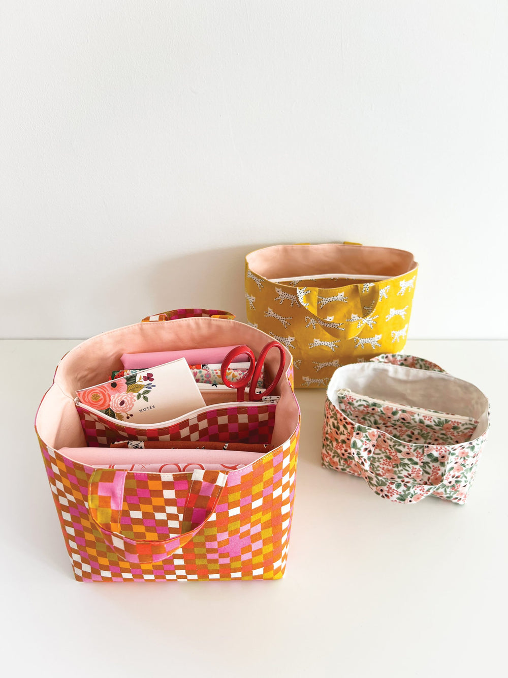 Photo showing the Zip, Divide It! Basket sewing pattern from Lou Orth Designs on The Fold Line. A storage basket pattern made in quilting cotton fabrics, featuring handles, zippered divider, fully lined, and 3 sizes.