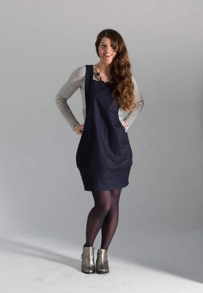 Woman wearing the Scoop Pinafore sewing pattern from Sew Different on The Fold Line. A sleeveless tunic dress pattern made in cotton, linen, denim, corduroy, velvet, wool or double knit fabrics, featuring a square neckline, scooped sides which house large