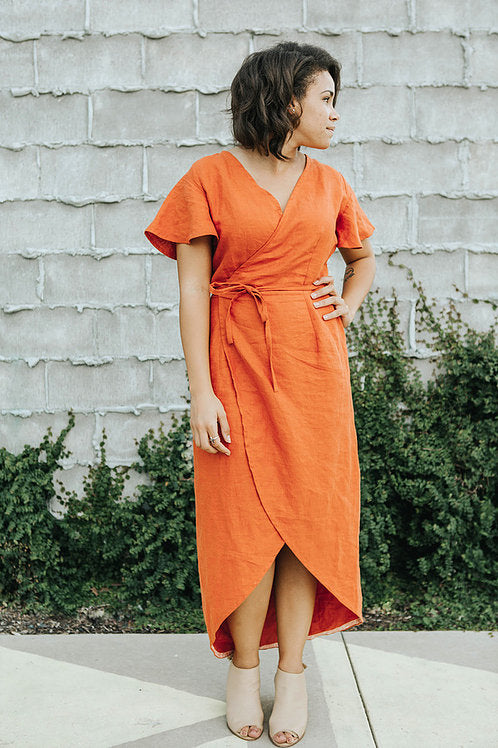 Woman wearing the CharliAnne Wrap Dress sewing pattern from Sew To Grow on The Fold Line. A dress pattern made in linen, rayon, voile or lawn fabrics, featuring a flutter sleeve, front and back darts, maxi tulip hem, V-neck and self-fabric wrap tie closur