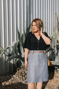 Woman wearing the Stella Skirt sewing pattern from Sew To Grow on The Fold Line. A skirt pattern made in linen, corduroy or denim fabrics, featuring topstitched patch pockets, chunky belt loops, deep hem, invisible side zip closure and knee length hem.