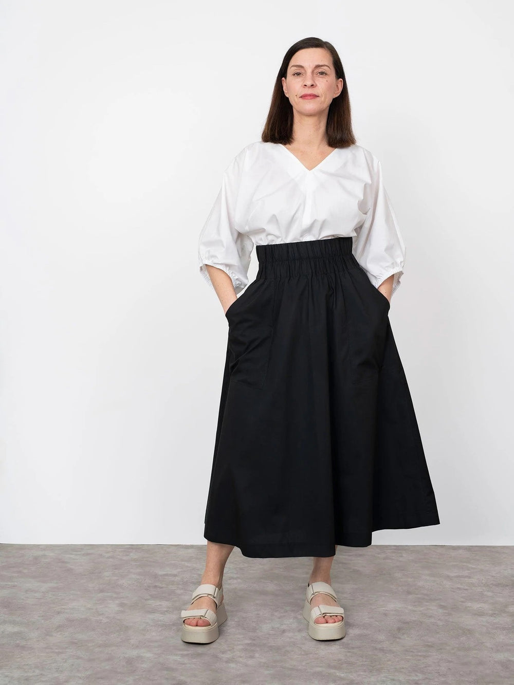 Woman wearing the V-neck Cuff Top sewing pattern from The Assembly Line on The Fold Line. A top pattern made in cotton, silk, lawn, linen, crepe de chine or wool crepe fabrics, featuring a V-neck, full gathered sleeves with elasticated mid length cuffs an