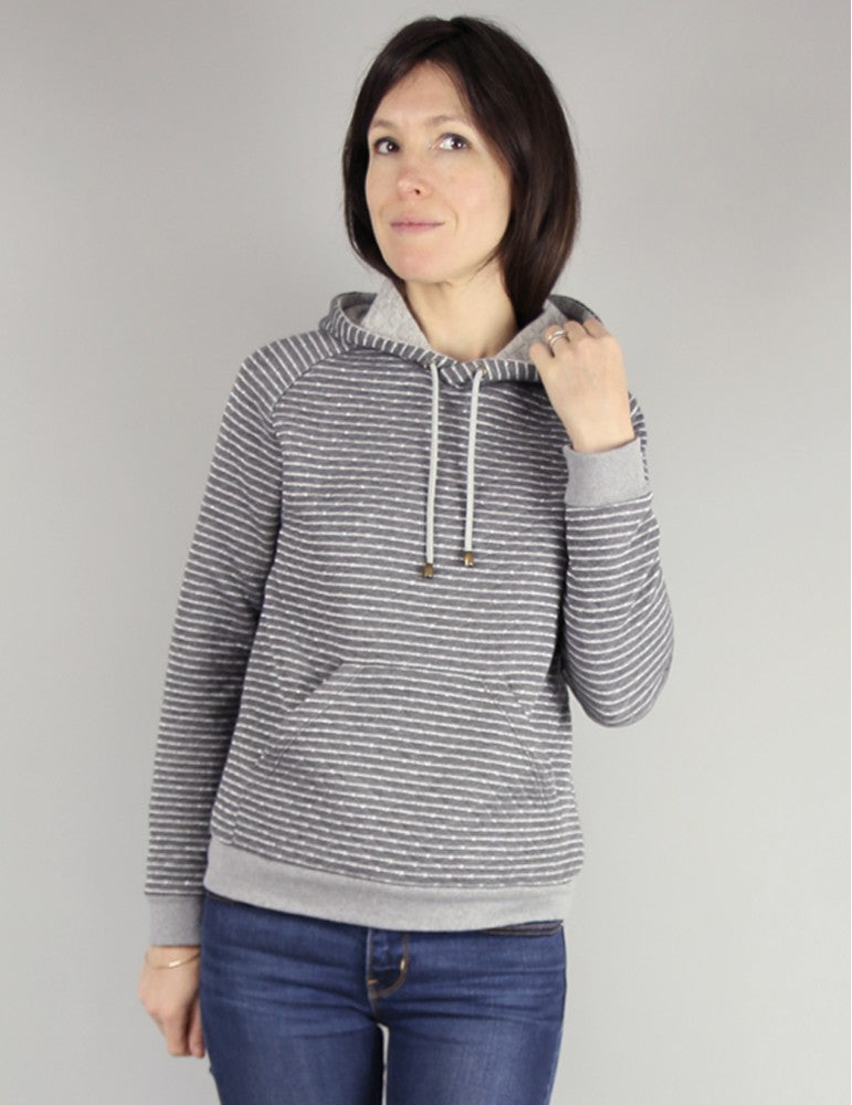 Woman wearing the Icone Sweatshirt and Cardigan sewing pattern by Atelier Scammit. A sweatshirt pattern made in medium to heavy weight sweatshirt fabric or boucle knits, featuring a slightly curved raglan sleeve, ample hood, kangaroo pockets and full leng