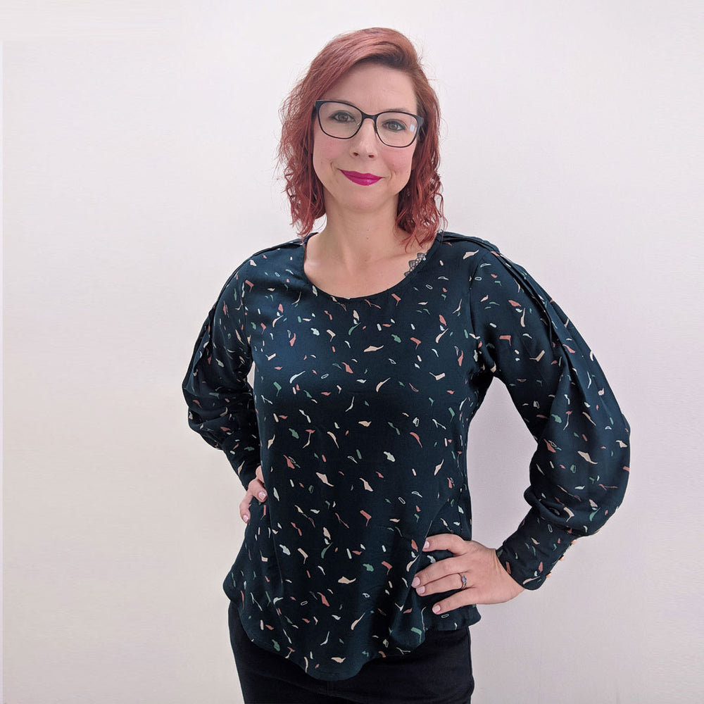 Woman wearing the Josie Blouse sewing pattern by Experimental Space. A blouse pattern made in rayon, viscose, crepe or georgette fabrics, featuring a trio of pretty pleats running over the shoulder and down into the sleeve. They then open up to a floaty b
