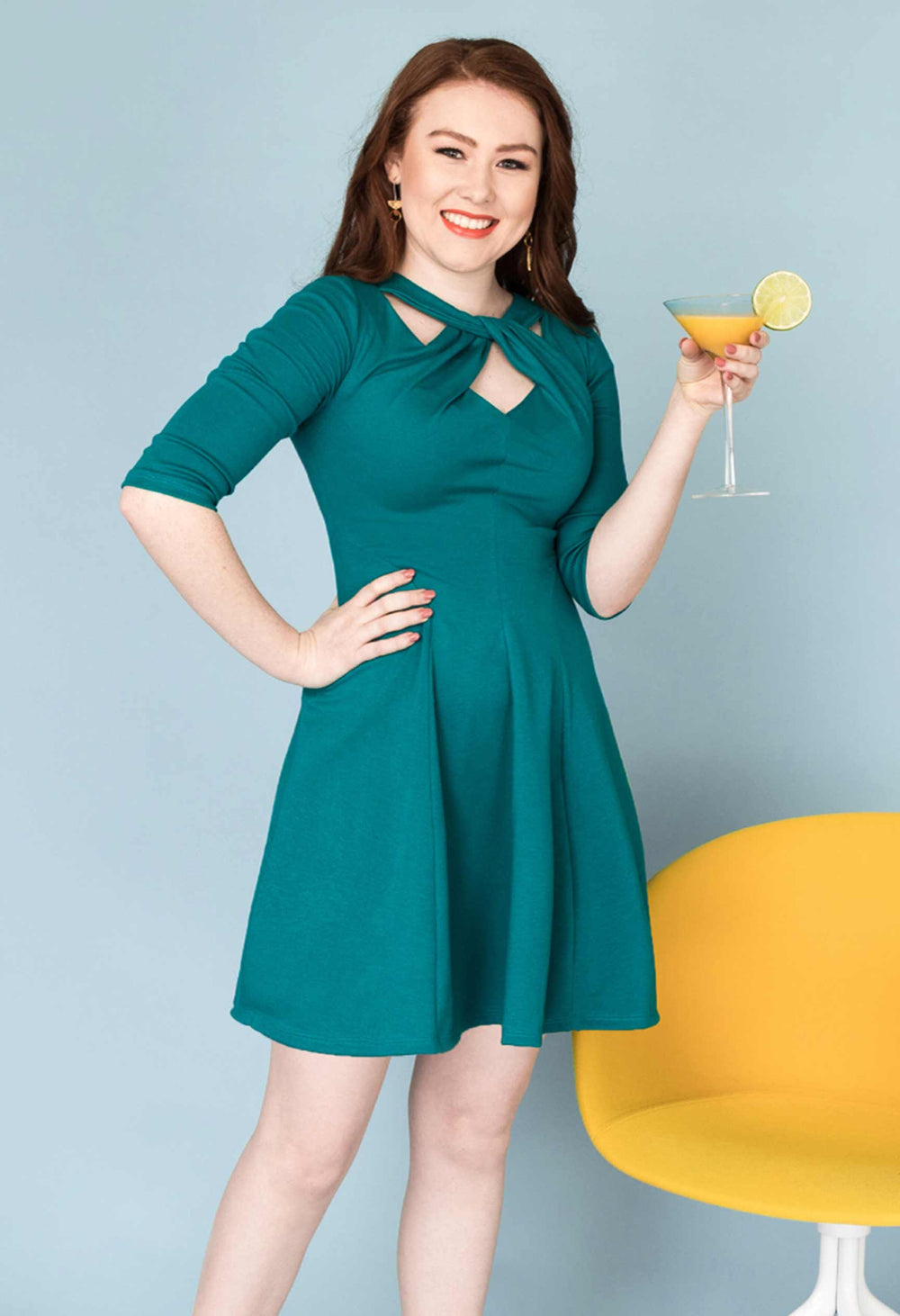 Woman wearing the Martini Twist Dress sewing pattern from Our Lady of Leisure on The Fold Line. A dress pattern made in medium-weight, medium stretch knit fabrics, featuring a twisted neckline, ¾ length sleeves, above knee length, fitted bodice, flared sk