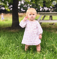 Child wearing the Child/Baby Peasant Dress sewing pattern from Elemeno Patterns on The Fold Line. A dress pattern made in gauze or light linen fabrics, featuring a draw string neckline, relaxed fit and gathered sleeves with an elasticated cuff.