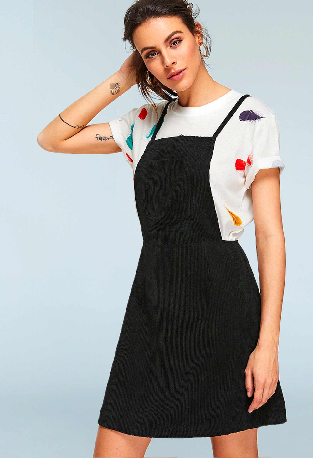 Woman wearing the Rickey Pinafore Dress sewing pattern from Our Lady of Leisure on The Fold Line. A pinafore dress pattern made in canvas, denim, corduroy, chambray, lawn, broadcloth or jacquard fabrics, featuring an above knee length, front patch pocket,