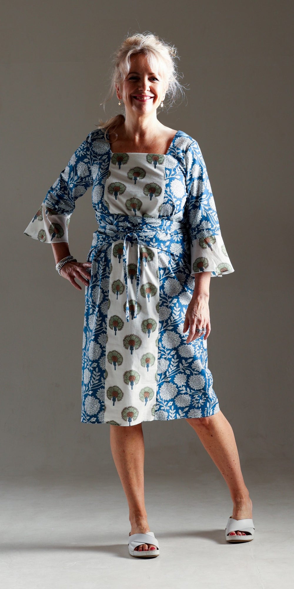 Woman wearing the Tuk Tuk Dress sewing pattern from Sew Different on The Fold Line. A faux wrap dress pattern made in lightweight cotton, viscose, rayon, and lightweight linen fabrics, featuring a square-neck, side wings extending into narrow waist ties, 