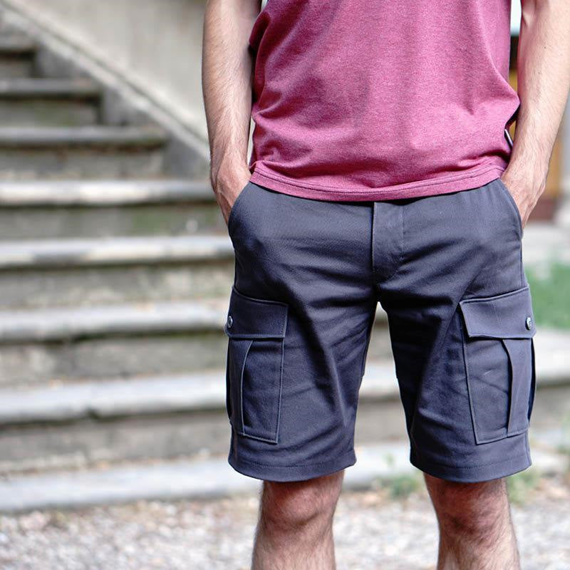 Man wearing the Men's Cargo Shorts sewing pattern from Wardrobe by Me on The Fold Line. A cargo shorts pattern made in cotton, linen, canvas or denim fabrics, featuring side pockets, pleated side pockets, back welt pockets, front zip fly and faced waistli