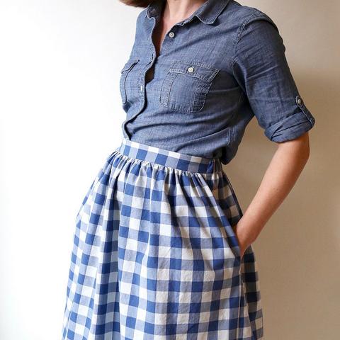 Woman wearing the Cleo Skirt sewing pattern from Made by Rae on The Fold Line. A gathered skirt pattern made in lawn, voile, double gauze, corduroy, cottons or sateen fabric, featuring a flat-front waistband with elastic in the back, knee-length finish, cut-out pockets and contrasting hem band.
