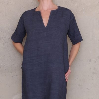 Woman wearing the Short Sleeved Dress sewing pattern by Ann Normandy. A dress pattern made in heavy, rustic linens, if using a lighter weight fabric, consider lining the dress, featuring elbow length sleeves, V-neck, in-seam pockets and relaxed fit.