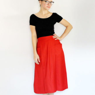 Woman wearing the Patti Pocket Skirt sewing pattern by Amy Nicole. A skirt pattern made in medium to heavy weight woven fabrics such as denim, twill, brocade, linen, quilting cotton and suiting fabrics, featuring a combination pleated and flared skirt with popped-out, deep front pockets, high waist and a side seam zipper.