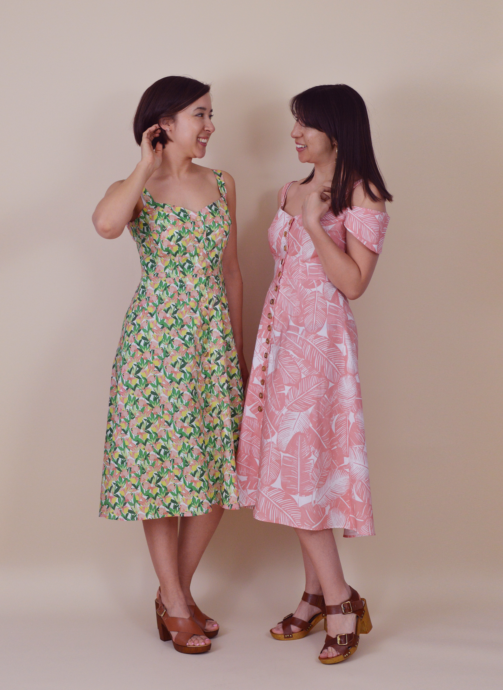 Women wearing the Kew Dresses sewing pattern from Nina Lee on The Fold Line. A fit and flare dress pattern made in rayon, viscose, crepe, linen blends, lightweight cotton, denim or corduroy fabrics, featuring shoulder straps with optional cold shoulder short sleeves, square neckline with a central V dip, full length button front closure and high low hemline.