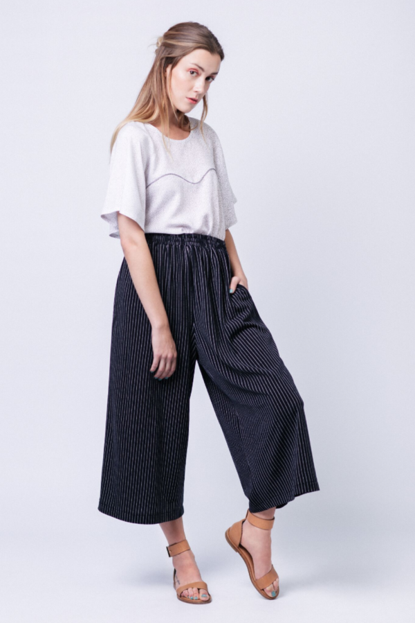 Woman wearing the Ninni Culottes sewing pattern from Named on The Fold Line. A culottes pattern made in light weight or medium weight drapey knit or woven fabrics, featuring a relaxed fit, elasticated waist, side pockets and mid shin length.