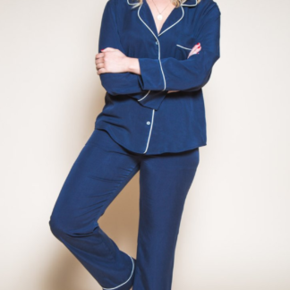 Woman wearing the Carolyn Pajamas sewing pattern by Closet Core Patterns. A Pyjama pattern made in cotton flannel, linen, cottons, lawn or silk fabric featuring a classic notched collar, curved hem, breast pocket and button front top. The straight-legged trousers have an elasticated waist, both have piping detail.