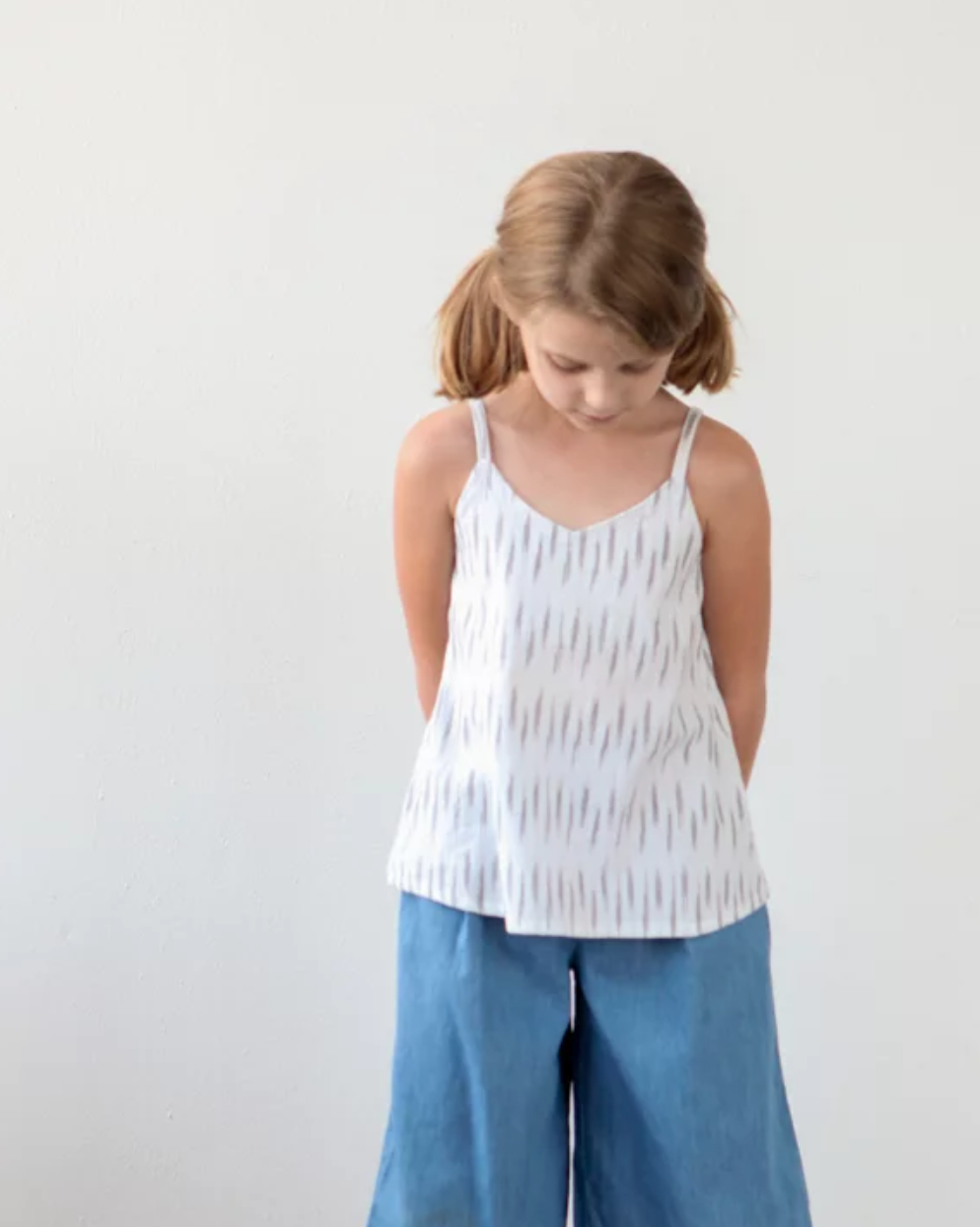 Girl wearing the Children’s Mini Ogden Cami sewing pattern by True Bias. A camisole pattern made in cotton voile, cotton lawn, linen or double gauze fabric featuring a soft V neck and spaghetti straps over each shoulder.