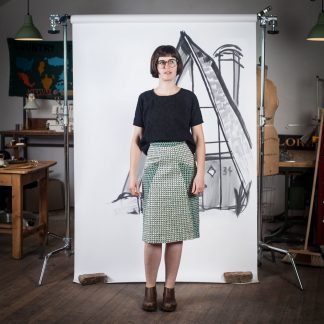 Woman wearing the A-Frame Skirt sewing pattern by Blue Prints for Sewing. A pencil skirt pattern made in denim, twill, sateen, linen, corduroy, rayon challis or linen blend fabrics, featuring a knee length finish, front pockets and kick pleat at the centre back seam.