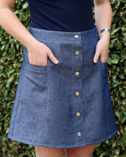 Woman wearing the Ally Skirt sewing pattern by Blue Dot Patterns. A fitted, six gore skirt pattern made in medium weight denim, corduroy, twill, linen or poplin fabrics, featuring a button front, top stitching and pockets.