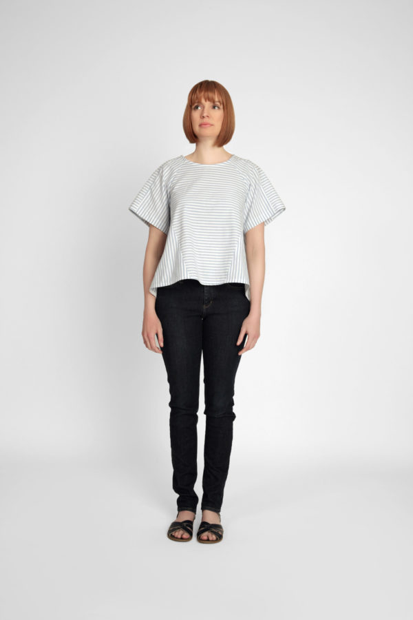 Woman wearing the Collins Top pattern from In the Folds on The Fold Line. A top pattern made in linen, linen blends, cotton, gauze, chambray, sateen, crepe de chine or viscose fabrics, featuring a loose-fitting trapeze-shape, round neck, high-low hem, centre-back opening with button and loop closure and three-piece raglan sleeve.