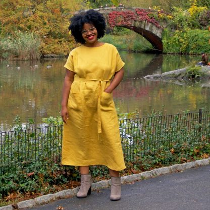 Woman wearing the Lottie Dress sewing pattern by Christine Haynes. A pullover, sleeveless dress pattern made in linen, lawn, rayon or Tencel fabrics, featuring a loose fit, short sleeves, front patch pockets, waist cinching belt and jewel neckline.