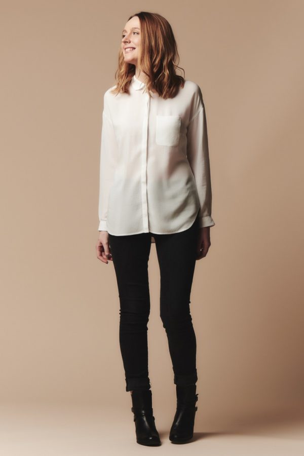 Woman wearing the Melilot Shirt sewing pattern by Deer and Doe. A casual shirt pattern made in batiste, cotton satin, viscose, silk or flannel fabric featuring dropped shoulders, long sleeves with cuffs, and a rounded collar.