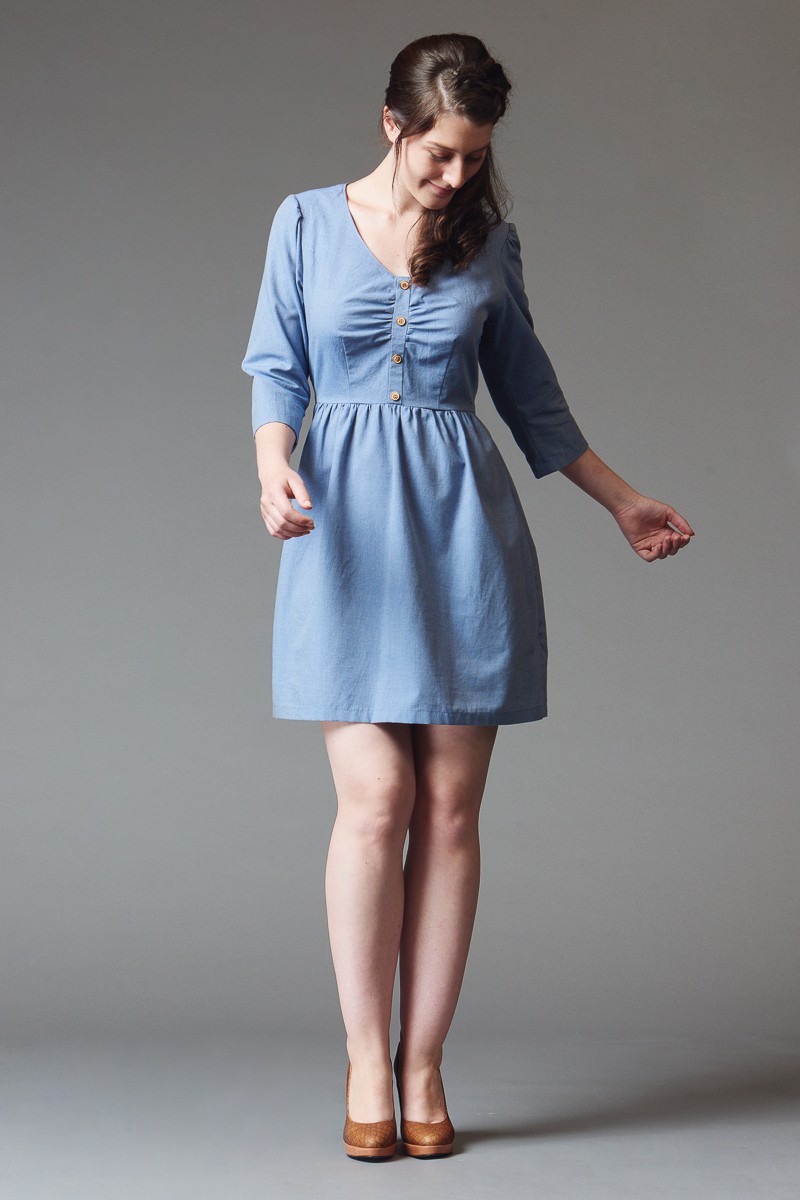Woman wearing the Sureau Dress sewing pattern by Deer and Doe. A dress pattern made in cotton poplin, chambray, lightweight linen or seersucker fabric featuring a mock button placket, bust gathers, three quarter length sleeves and a gathered skirt.