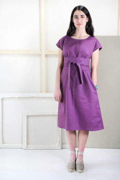 Woman wearing the Terrace Dress sewing pattern from Liesl + Co on The Fold Line. A dress pattern made in linen, double gauze, rayon, shirting, and quilting cotton fabrics, featuring a loose fit, bust darts, in-seam pockets, scoop neck, short sleeves, below knee length hem, and wide wrap-around sash.