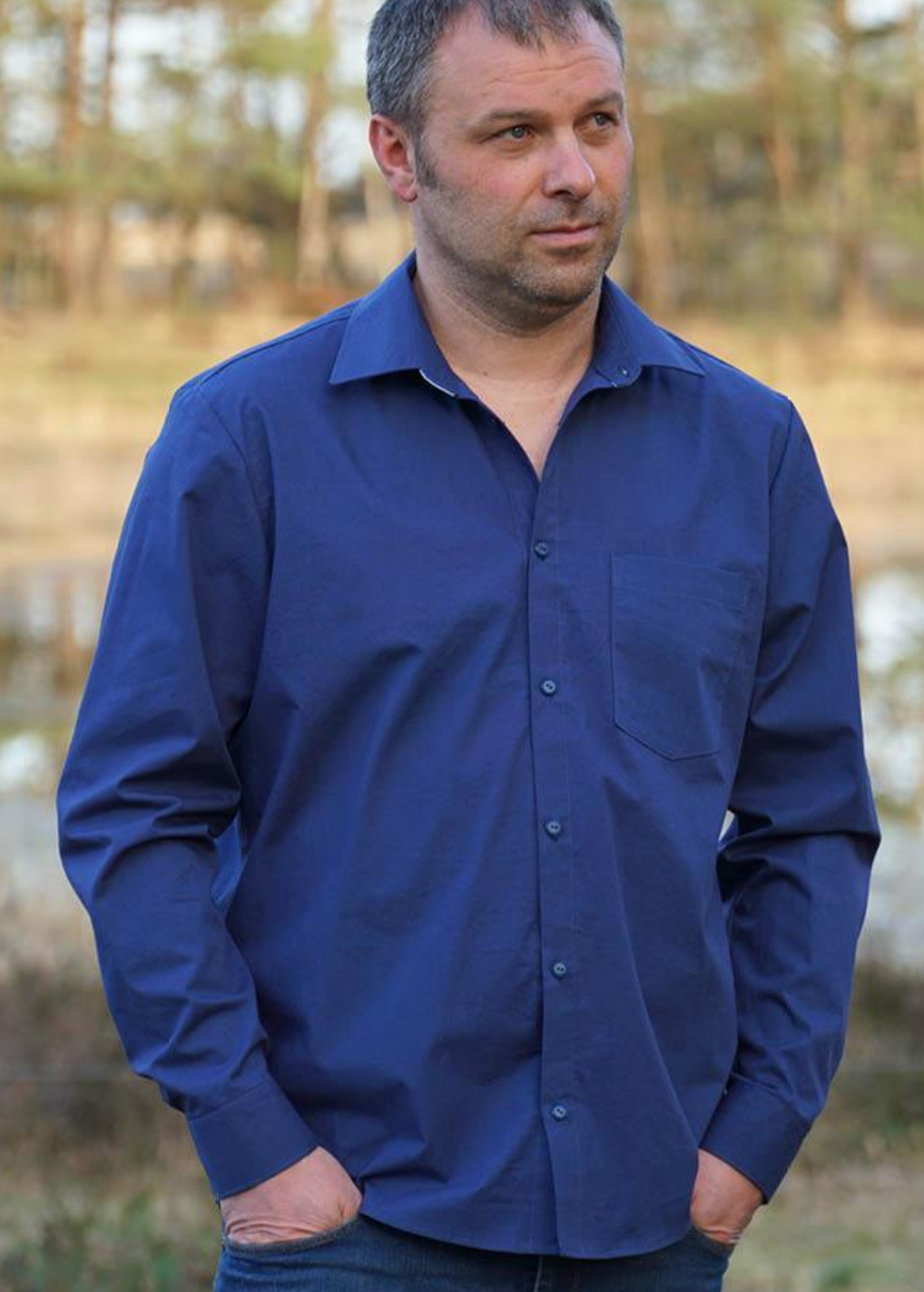 Man wearing the Men's Jensen Shirt sewing pattern from Wardrobe by Me on The Fold Line. A shirt pattern made in cotton, linen or silk fabrics, featuring a classic relaxed-fitting button-front shirt, with yoke, collar and stand, plus curved high low hem.