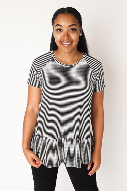 Woman wearing the Waterfall Raglan Top sewing pattern by Chalk and Notch. A dress pattern made in light to medium weight 75% – 100% stretch knit fabrics, featuring short sleeves, jewel neckline and ruffle.
