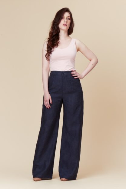 Woman wearing the Narcisse Pants sewing pattern by Deer and Doe. A trouser pattern made in lightweight twill, denim, linen or chambray fabric featuring a high waist, wide legs, inseam front pockets and decorative side stripes.
