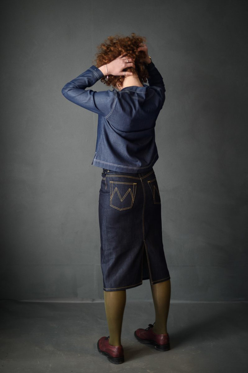 Woman wearing the Clementine sewing pattern by Merchant and Mills. A classic skirt pattern made in denim fabric featuring a slim fitting silhouette, back split, front and back pockets, fly zip and topstitching.